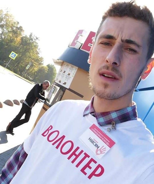 Волонтёр Максим с бейджем и в майке с надписью "волонтёр"
